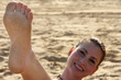 Girl foot with sand and her face in background. Cheerful photo