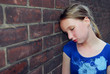 Photo: Young girl near brick wall looking upset Young girl near brick wall looking upset