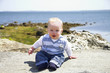 Cute boy sitting on a rock in front of the ocean