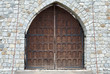 Old brown wooden gate in stone wall..