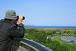Man looking through binoculars at a natural wetland area