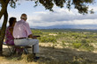 Old couple sitting on a bench, watching at the landscape