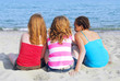 Portrait of three teenage girls sitting on a sandy beach