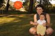 A mother with nine month old daughter with a ball.