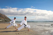 Young adult men with black belt practicing a Kata on the beach 