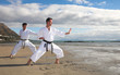 Photo: Young adult men with black belt practicing a Kata on the beach Young adult men with black belt practicing a Kata on the beach