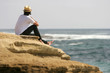 Man relaxing at the seaside, sitting on cliff near the sea