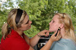 A makeup artist applying blush to a model 