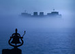 Close view of bell on dock with freighter boat in foggy distance