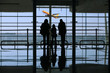 family looking to a airplane through the window in the airport