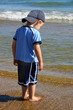 Young boy watches the water wash over his feet