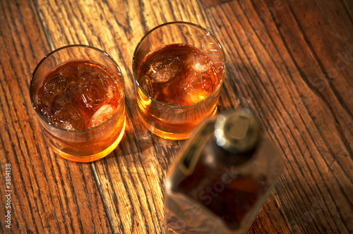 Two glasses from whisky and a bottle on a wooden table