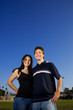 Photo: Smiling young couple embracing outdoors on a playing field Smiling young couple embracing outdoors on a playing field