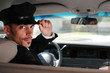 Handsome male chauffeur sitting in a car saluting a viewer Handsome male chauffeur sitting in a car saluting a viewer