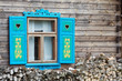 Opened window with decorative colorful shutters and logs below..