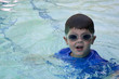 Photo: Cute boy swimming in pool wearing blue shirt and goggles Cute boy swimming in pool wearing blue shirt and goggles