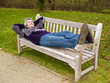 Relaxed middleaged man in a sweater and jeans lying on a bench