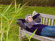 Relaxed middleaged man in a sweater and jeans lying on a bench