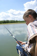 The boy with a fishing tackle on coast of the river