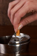 Hand finishing a cigarette in an ashtray