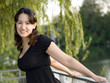 Smiling latin brunette girl in a black blouse outdoor portrait