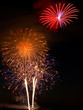 Red, gold, pink, blue fireworks above white rocket trails