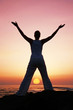 Woman in meditation pose at sunset with falling sun Woman in meditation pose at sunset with falling sun