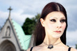 Gothic girl in cemetary with greenish chapel background