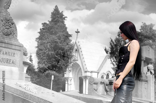 Photo: Long haired girl wearing black corset looking at tomb Long haired girl wearing black corset looking at tomb