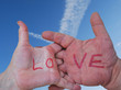 Male and female hands expressing love against sky