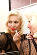 Woman putting on lipstick in front of a mirror