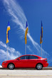 Red car, blue sky bacground and flags