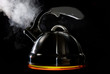 Tea kettle with boiling water on black background