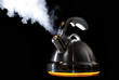 Tea kettle with boiling water on black background