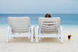 Two chaise-longue on the beach. One of them is empty.