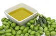 Olive oil in a bowl with fresh green olives