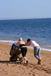 Two women pushing a pram on a beach