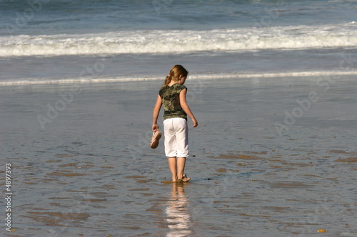 Photo: petite fille avec une queue de cheval qui regarde la mer petite fille avec une queue de cheval qui regarde la mer