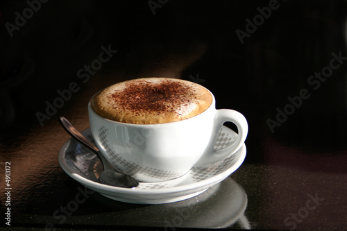 A cappuccino in a cup on a black table