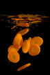Sliced carrots splashing into water on black backcground
