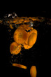 Sliced carrots splashing into water on black backcground