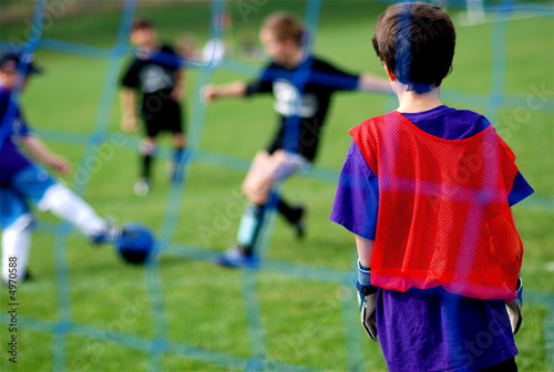 Photo: Young Goalie watching Kids Kick the Soccer Ball in front of Net Young Goalie watching Kids Kick the Soccer Ball in front of Net