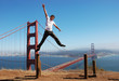 Happy young man jumping high next to the Golden Gate bridge