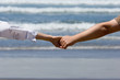 Young couple hands with the ocean waves background