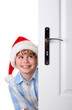 Boy with Santa's Hat peeking behind the door