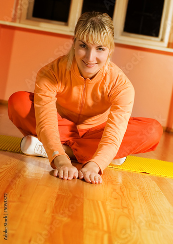 Beautiful fitness trainer sitting on a floor