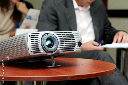 Projector on table with two person behind (horizontal)  