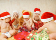 Group of adorable toddlers in Christmas hats packing presents