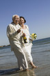 Senior newly weds walking in ocean