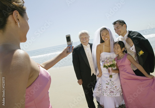 Photo: Bridesmaid photographing newly weds with family on beach Bridesmaid photographing newly weds with family on beach